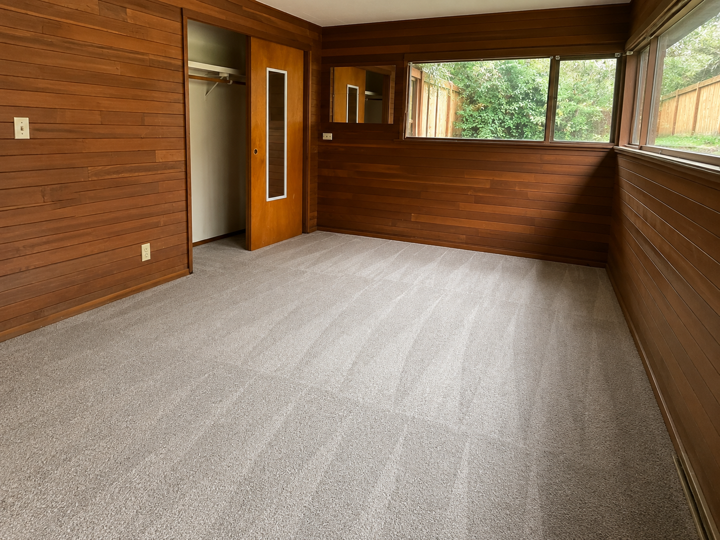 Clean bedroom with wood paneling and fresh carpet after professional cleaning