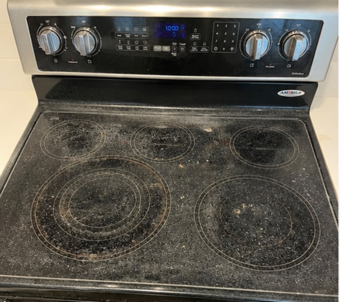 Glass stovetop with cooked-on residue before deep cleaning